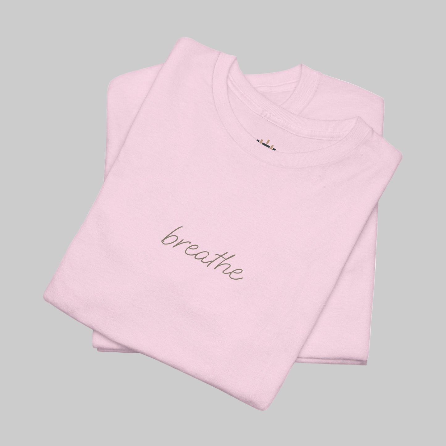 Folded pink t-shirt with 'breathe' text on a white background