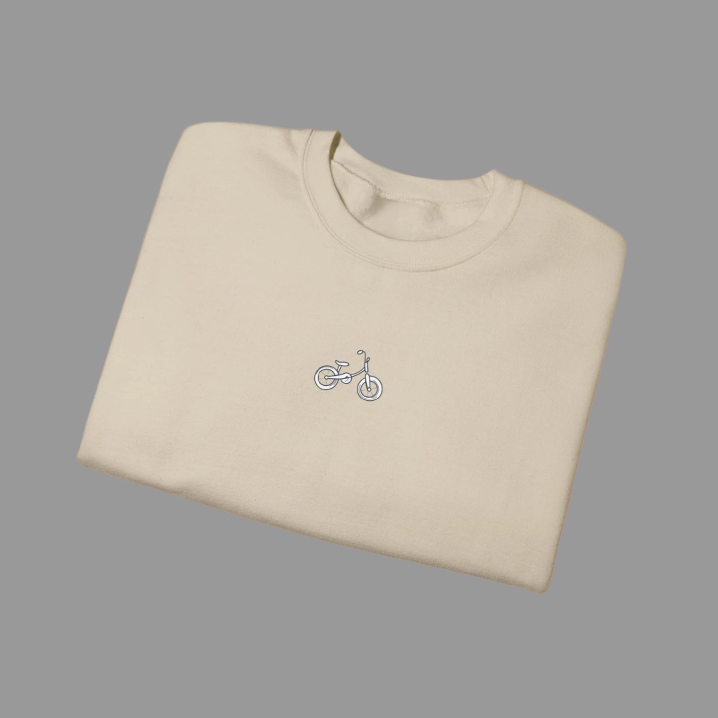 Folded beige t-shirt with a small bicycle logo on a white background