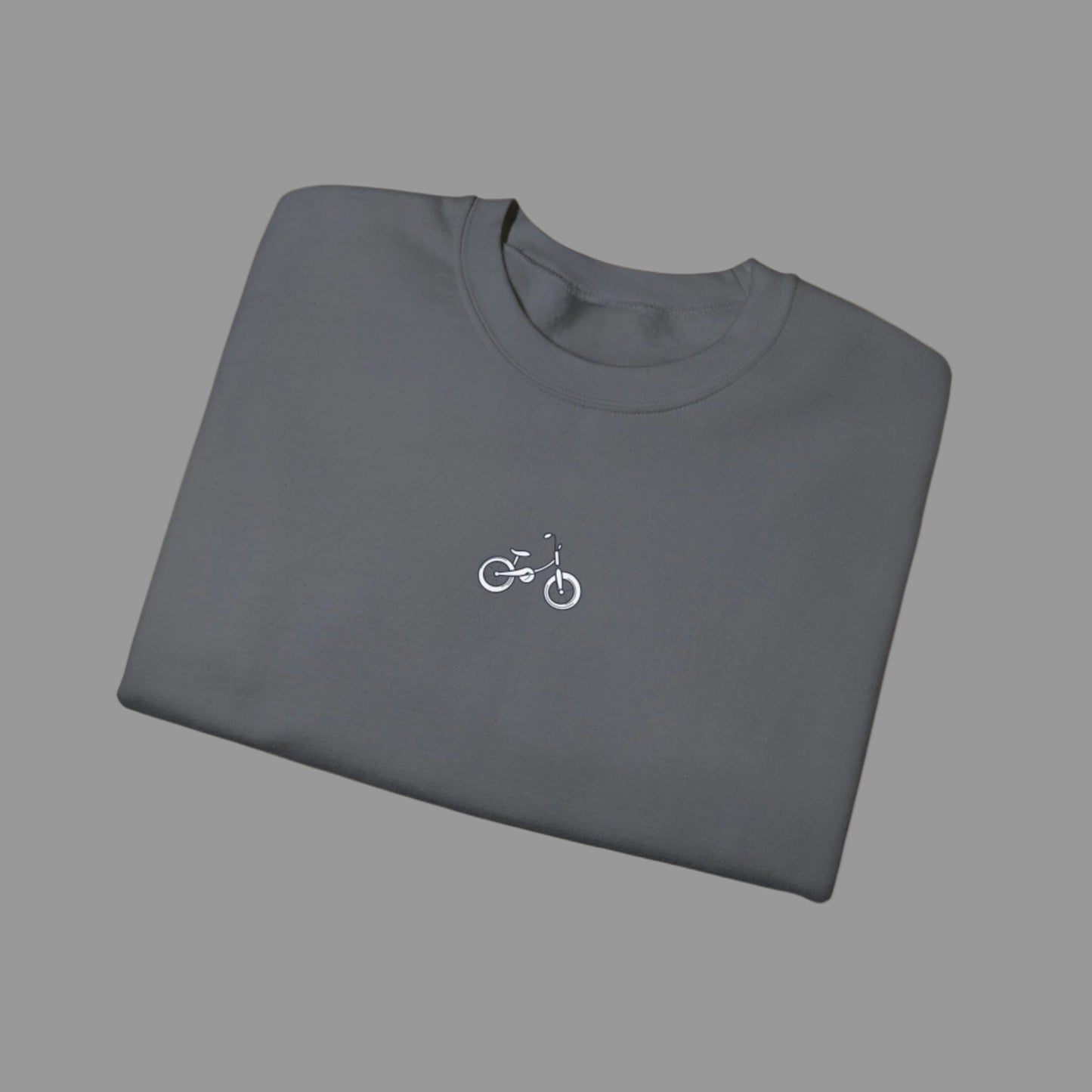 Folded gray t-shirt with a small bicycle logo on a white background