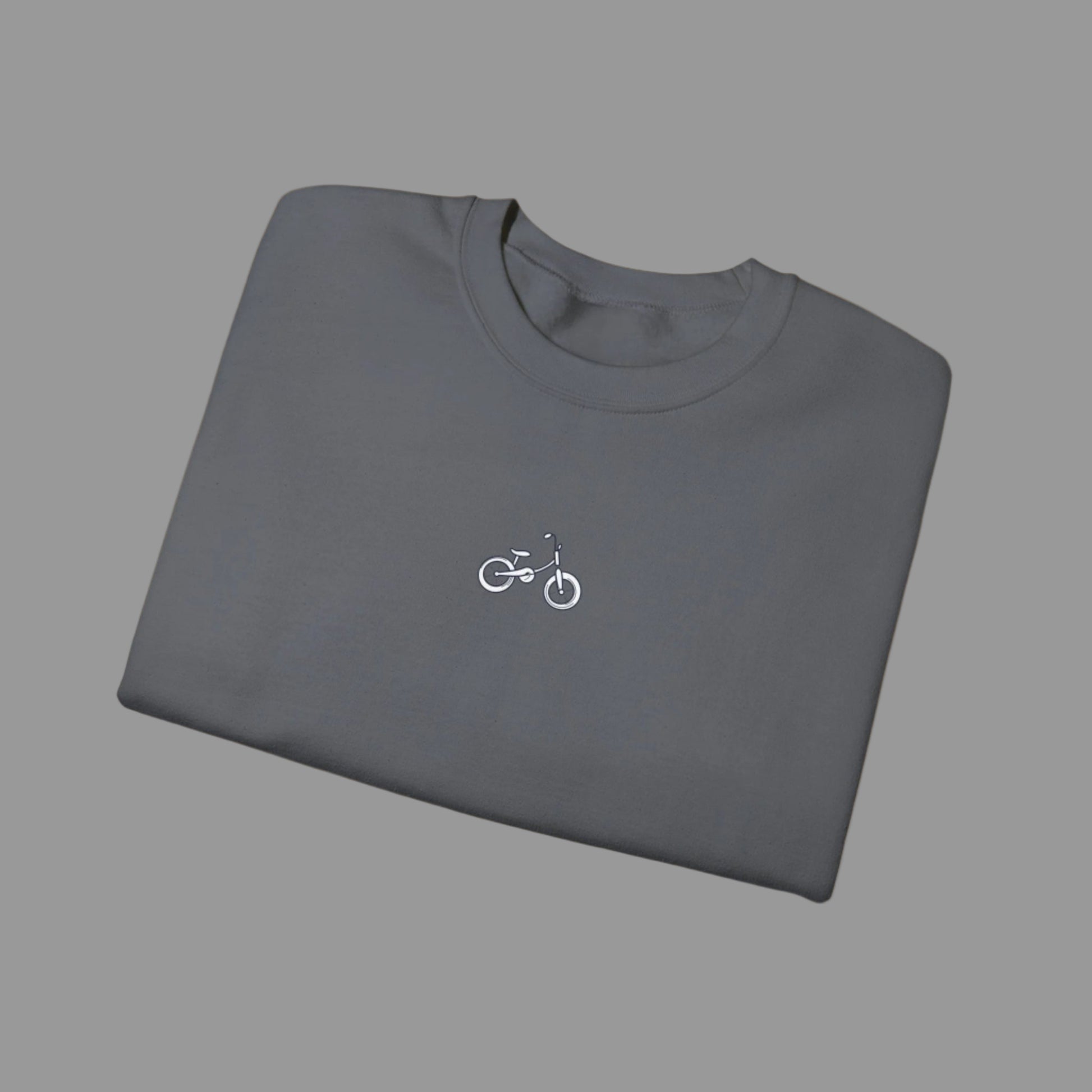 Folded gray t-shirt with a small bicycle logo on a white background