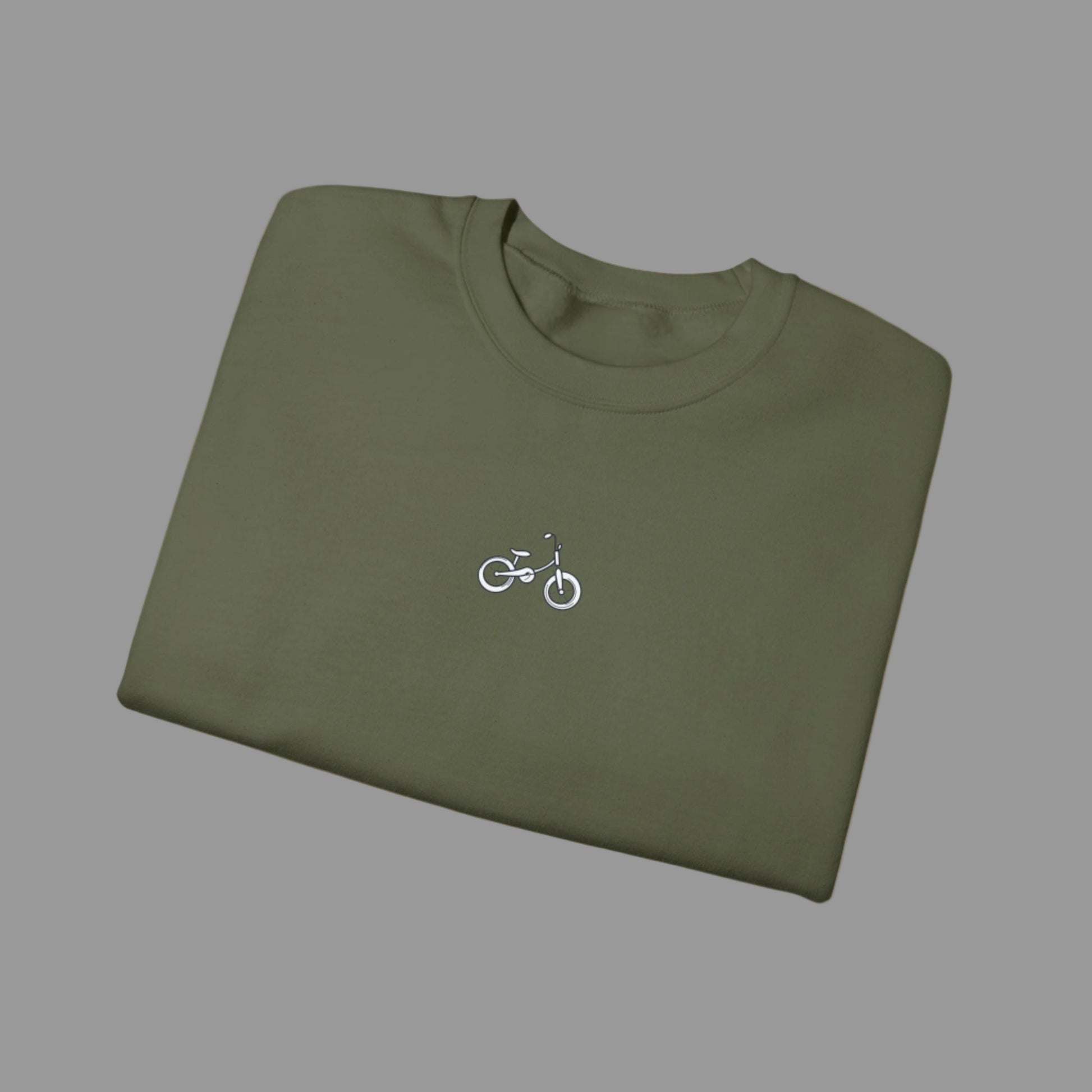 Folded green t-shirt with a small bicycle logo on a white background