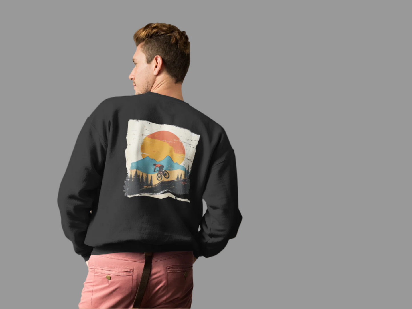 Person wearing a black sweatshirt with a graphic design on the back against a pink background