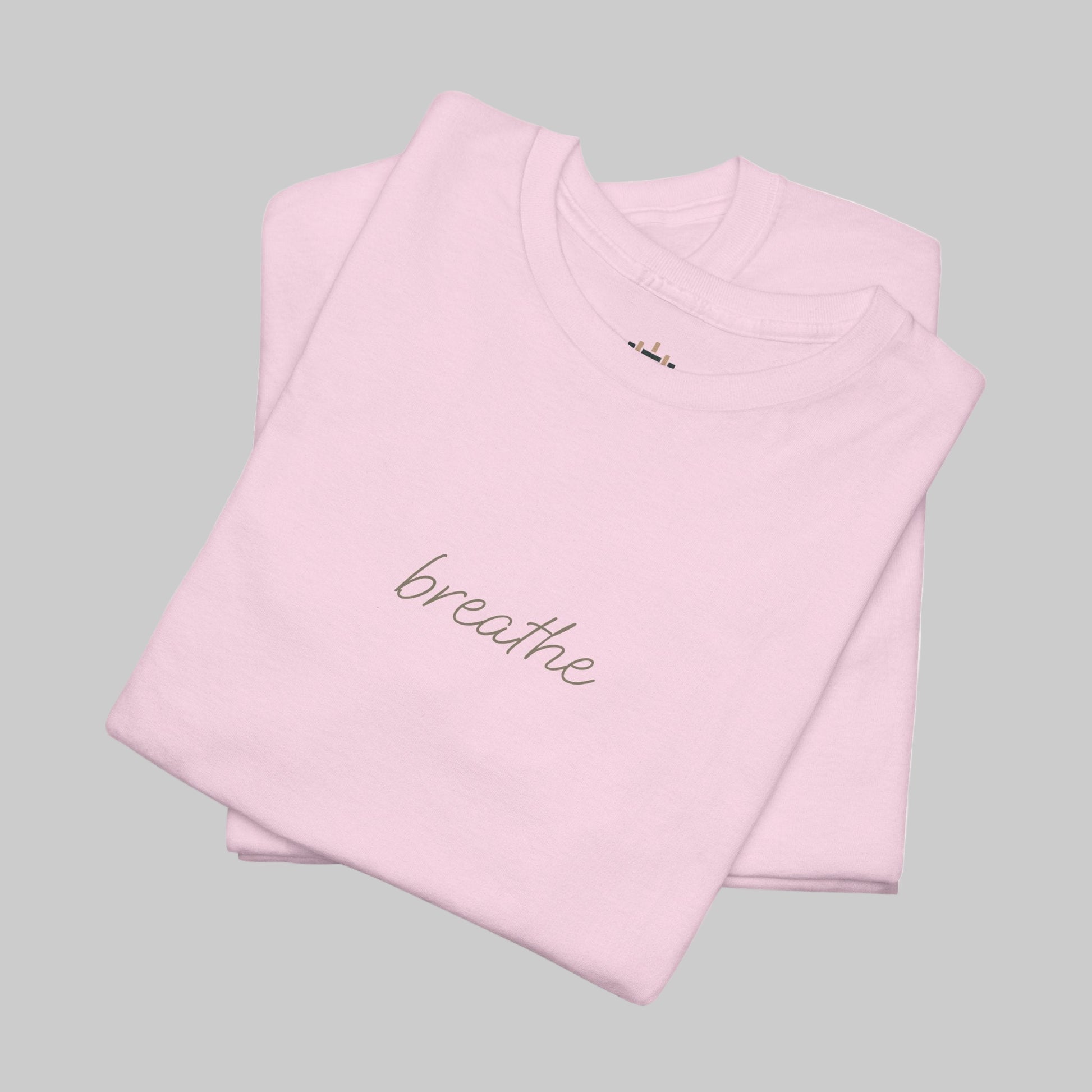 Folded pink t-shirt with 'breathe' text on a white background