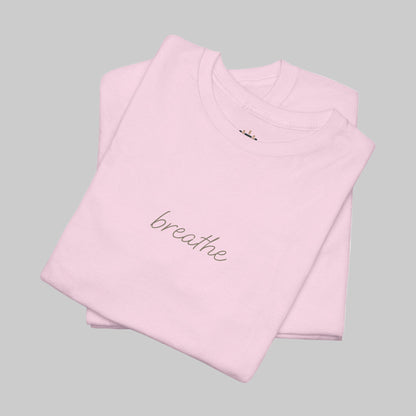 Folded pink t-shirt with 'breathe' text on a white background