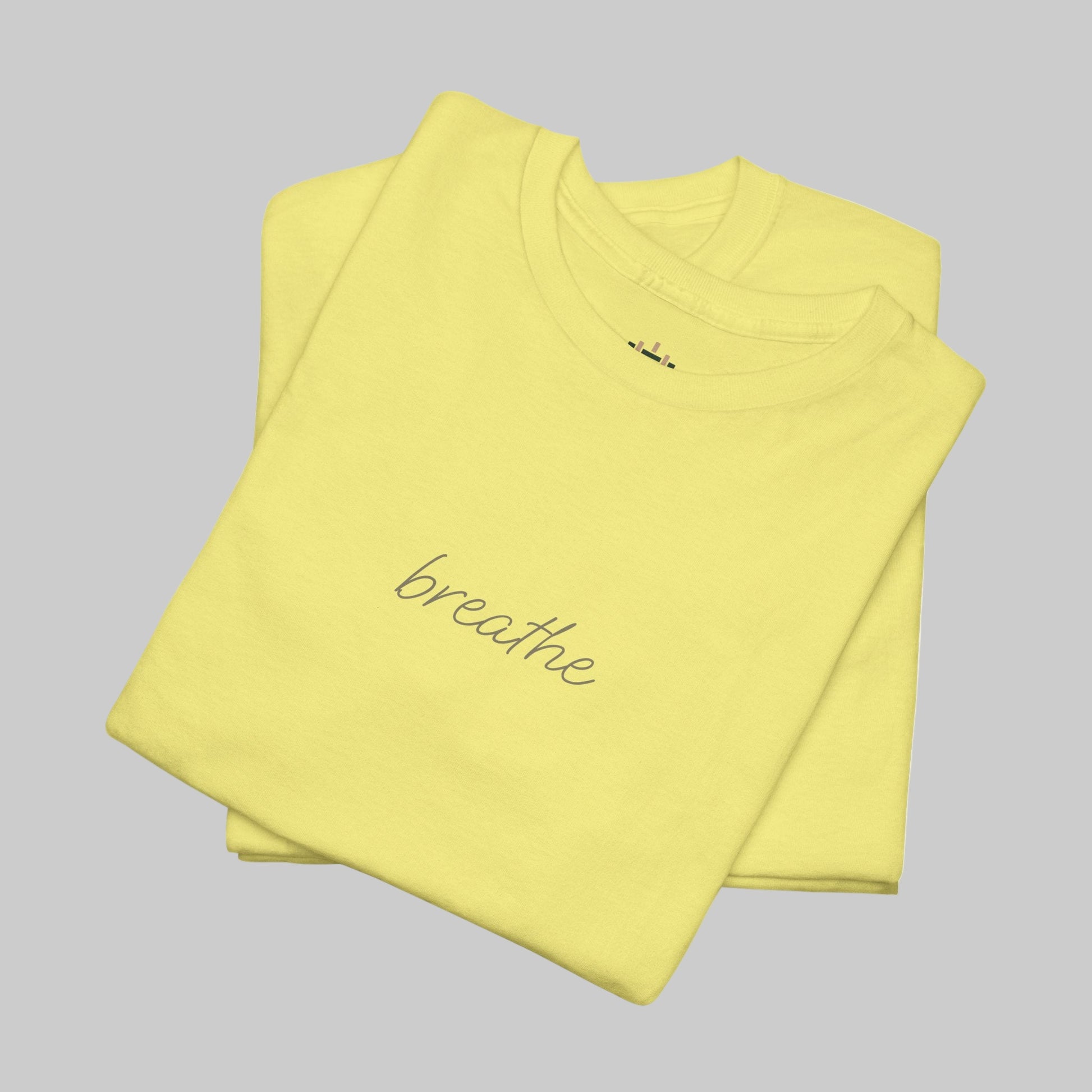 Folded yellow t-shirt with 'breathe' text on a white background