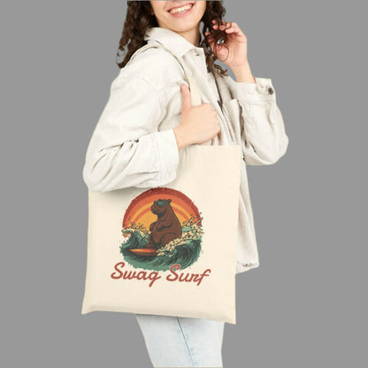 Woman holding a tote bag with a bear graphic and 'Swag Surf' text on a white background