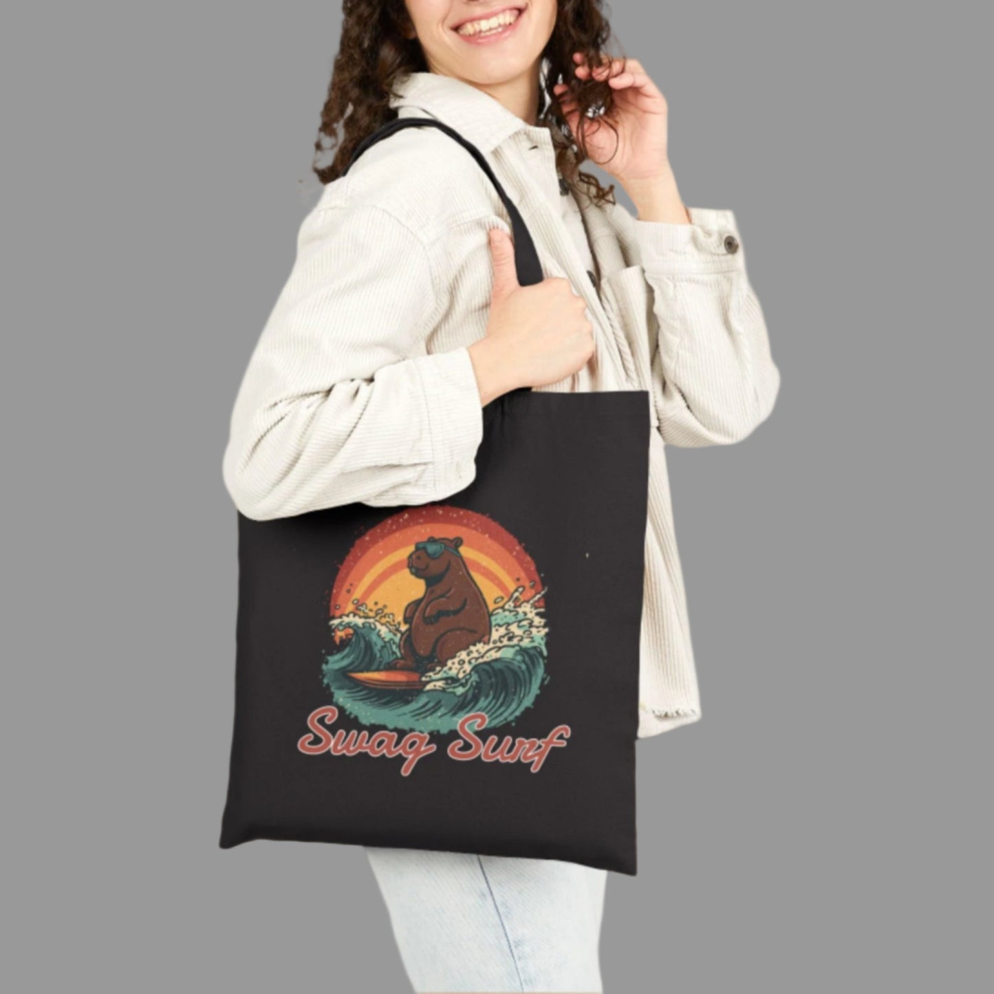 Woman holding a black tote bag with a bear and wave design, wearing a white jacket.