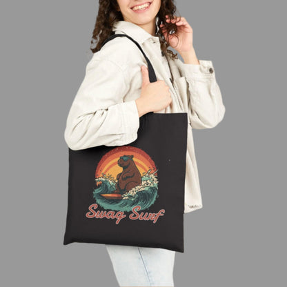 Woman holding a black tote bag with a bear and wave design, wearing a white jacket.