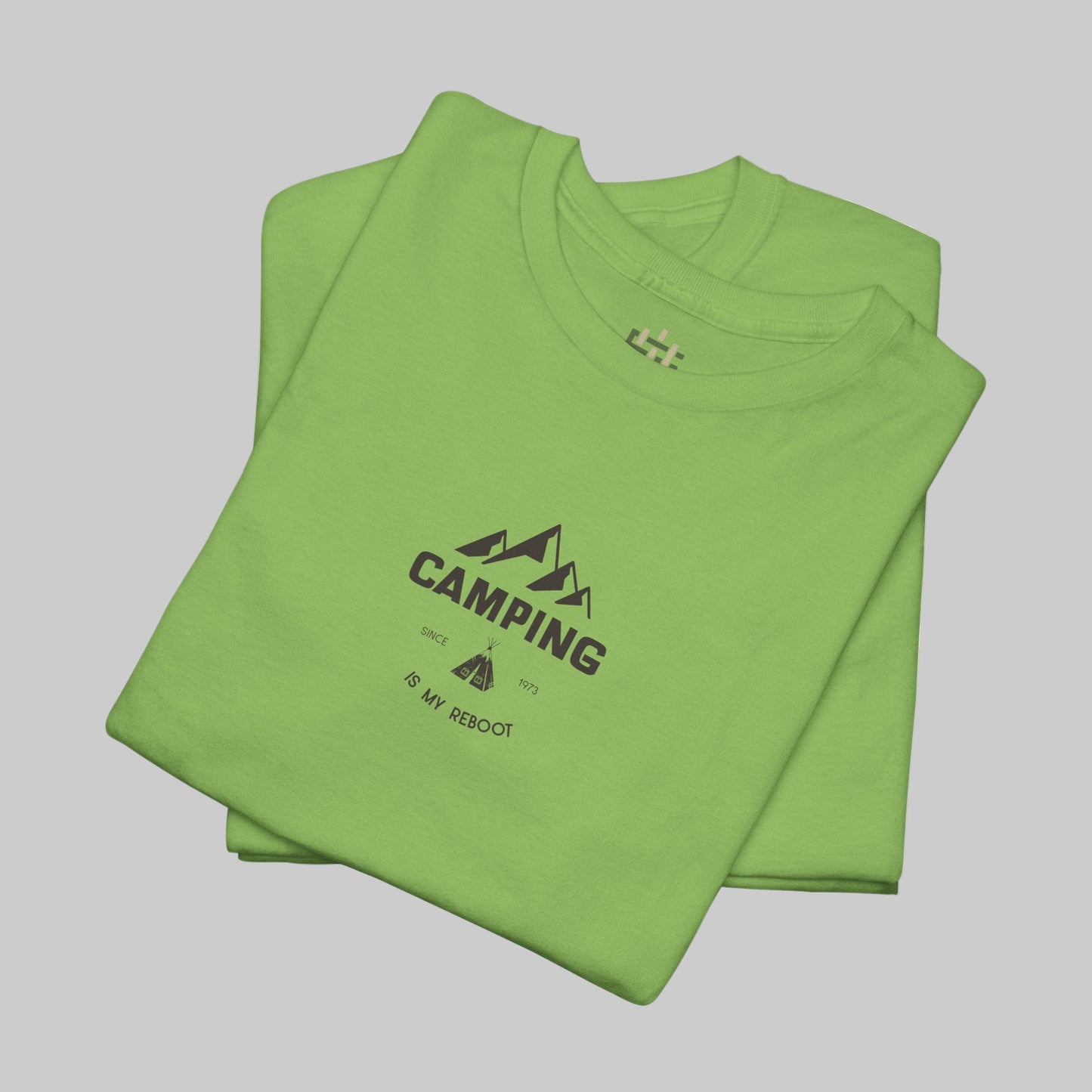 Folded green t-shirt with 'Camping is my Beach' text on a white background