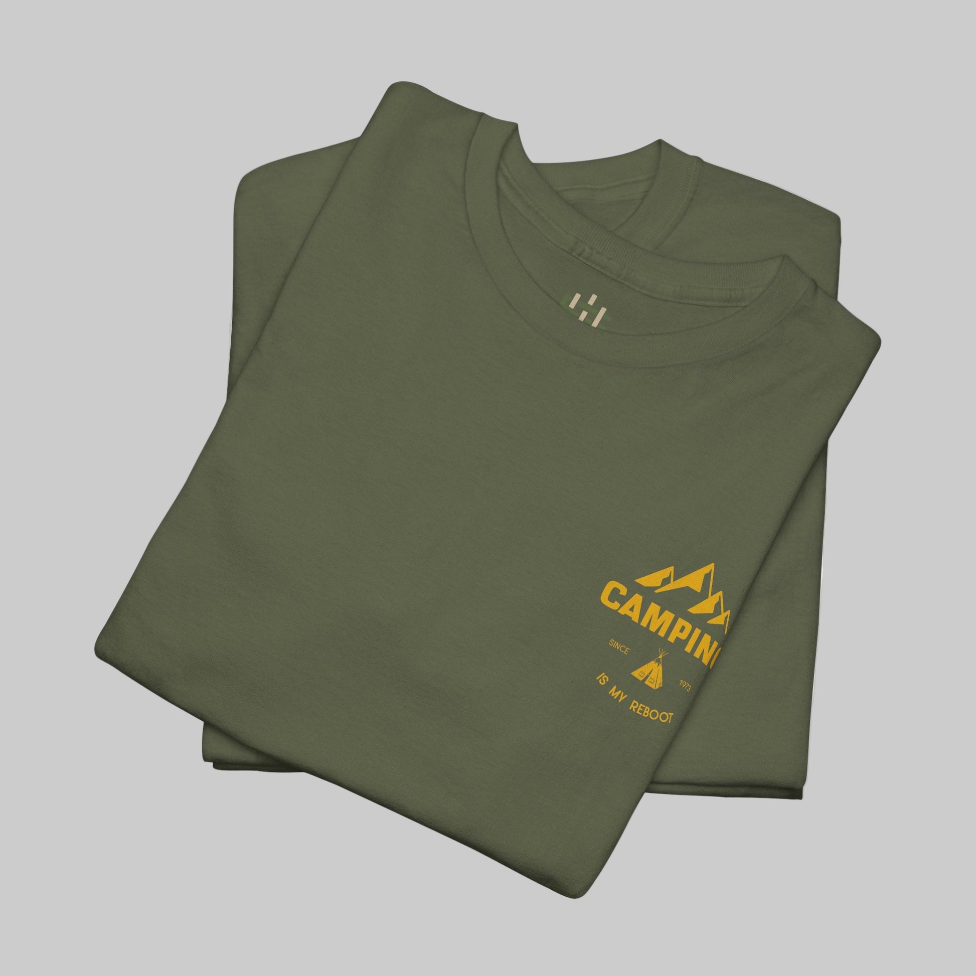 Folded green t-shirt with yellow 'Camping' logo on a white background