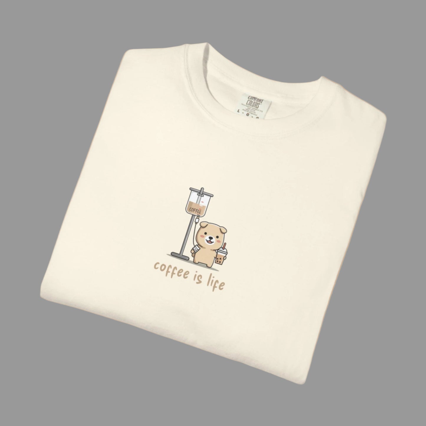 Folded cream-colored t-shirt with a bear and coffee grinder graphic and 'coffee is life' text on a white background.