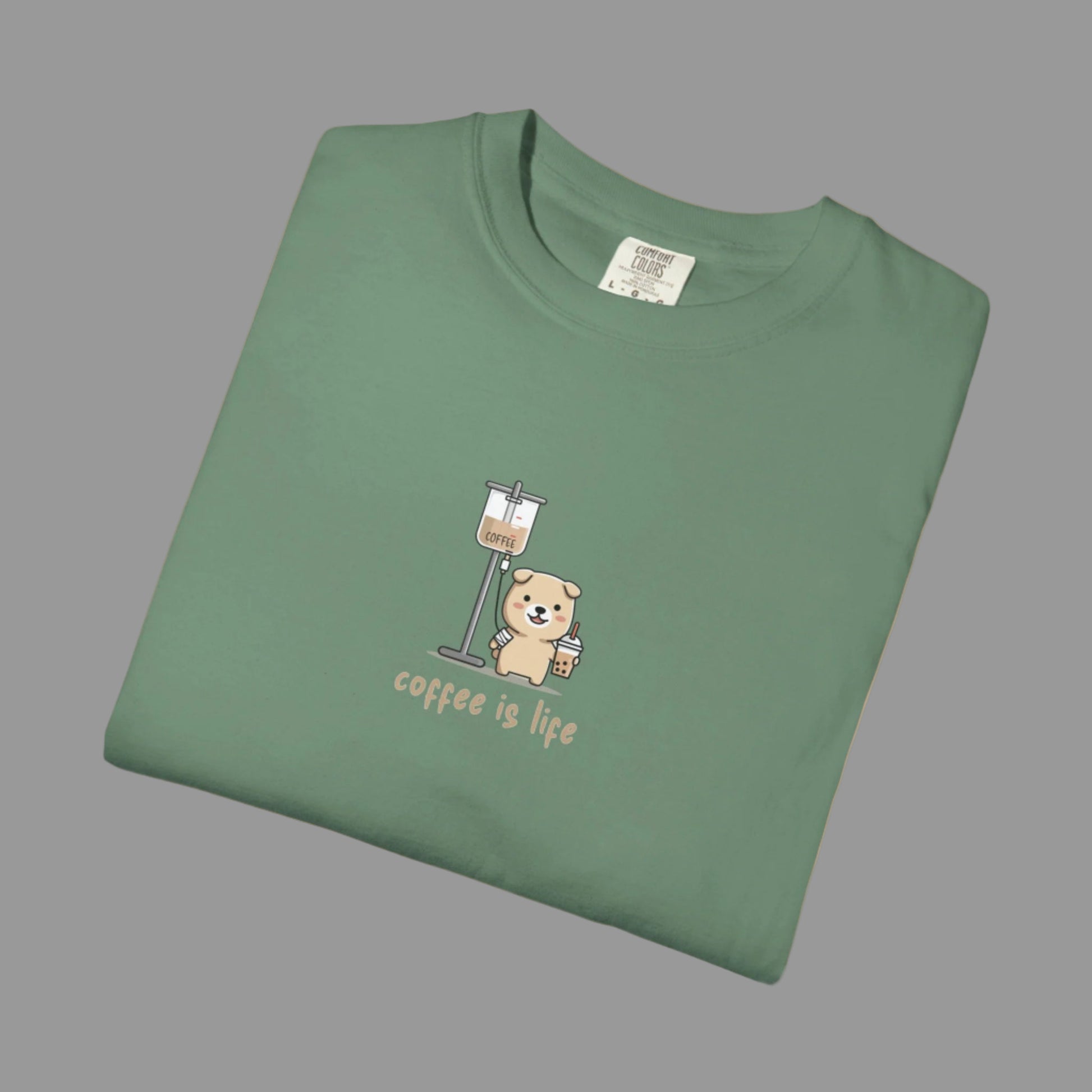 Folded green t-shirt with a bear and coffee cup graphic and 'coffee is life' text on a white background.