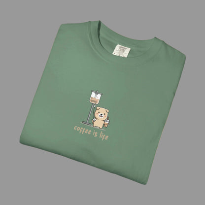 Folded green t-shirt with a bear and coffee cup graphic and 'coffee is life' text on a white background.