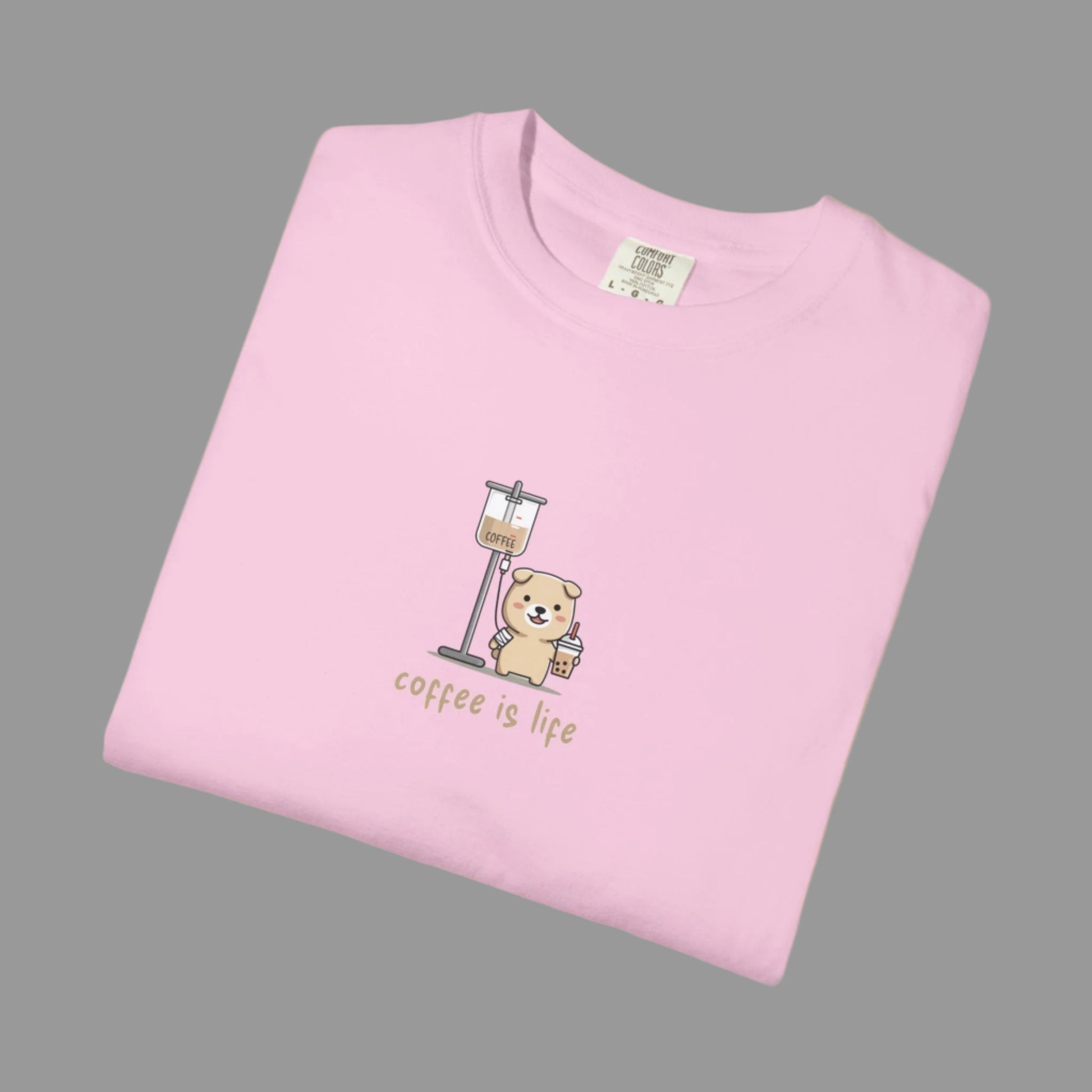 Folded pink t-shirt with a bear and coffee cup graphic and 'coffee is life' text on a white background.