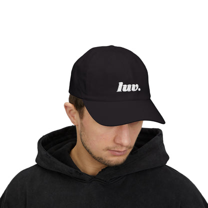 Man wearing a black cap with 'luv.' text on a white background