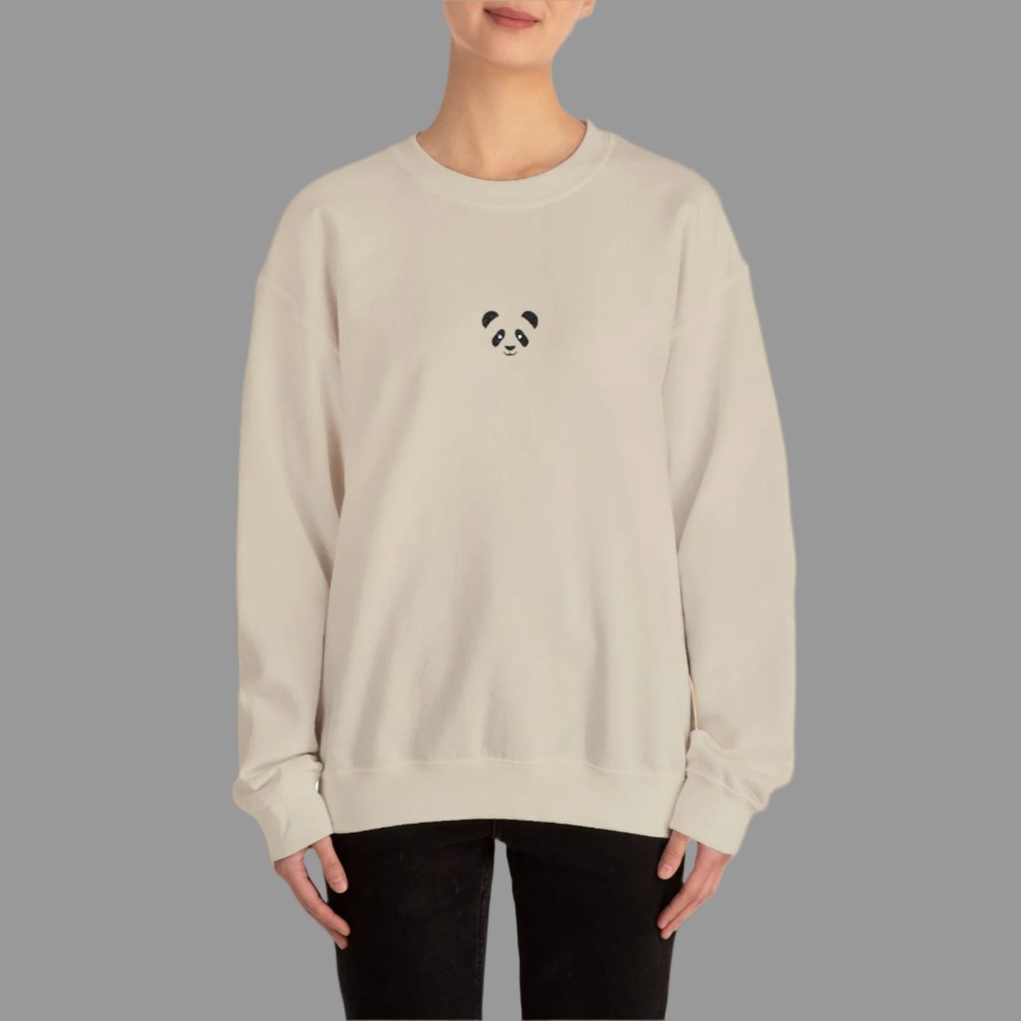 Person wearing a beige sweatshirt with a panda design on a white background