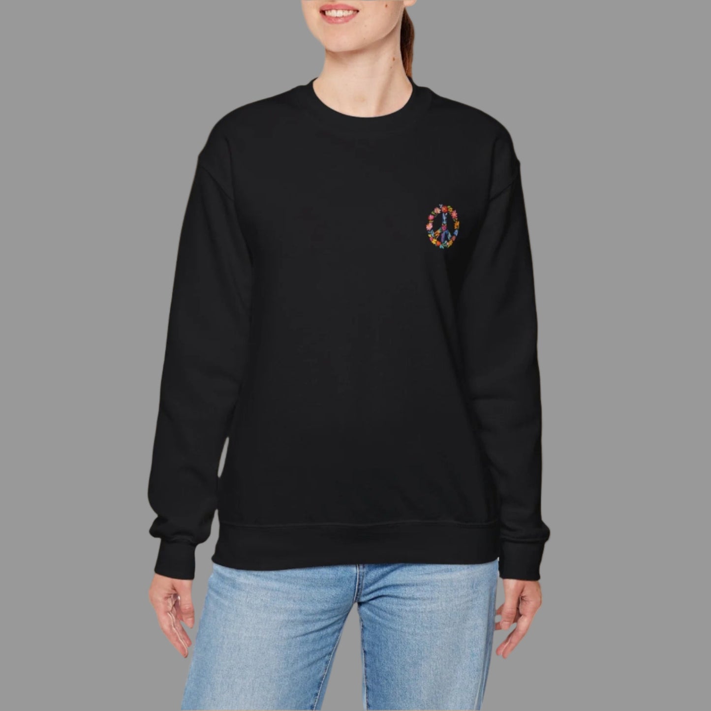 Person wearing a black sweatshirt with a peace symbol design on a white background