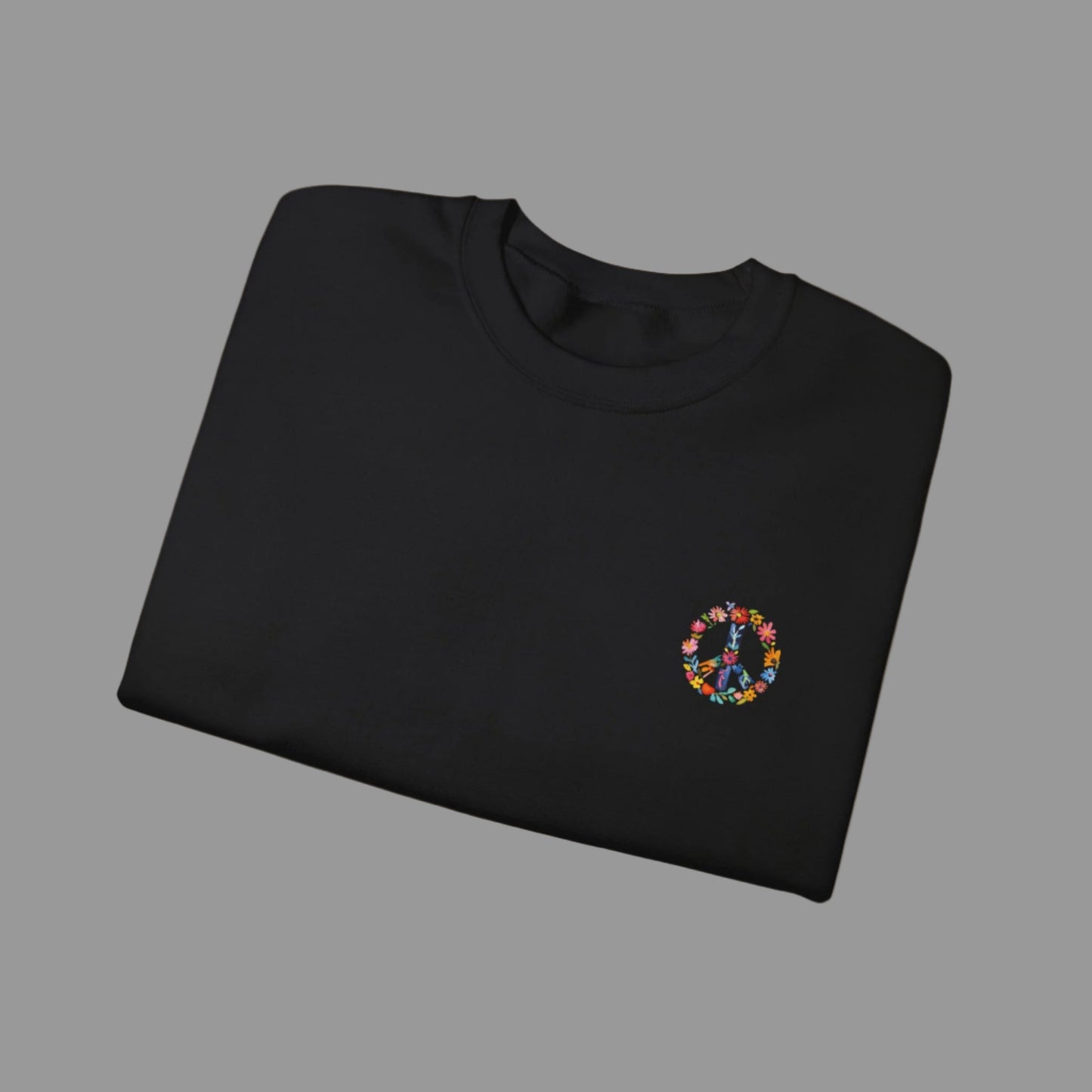 Folded black sweatshirt with a colorful peace symbol on a white background
