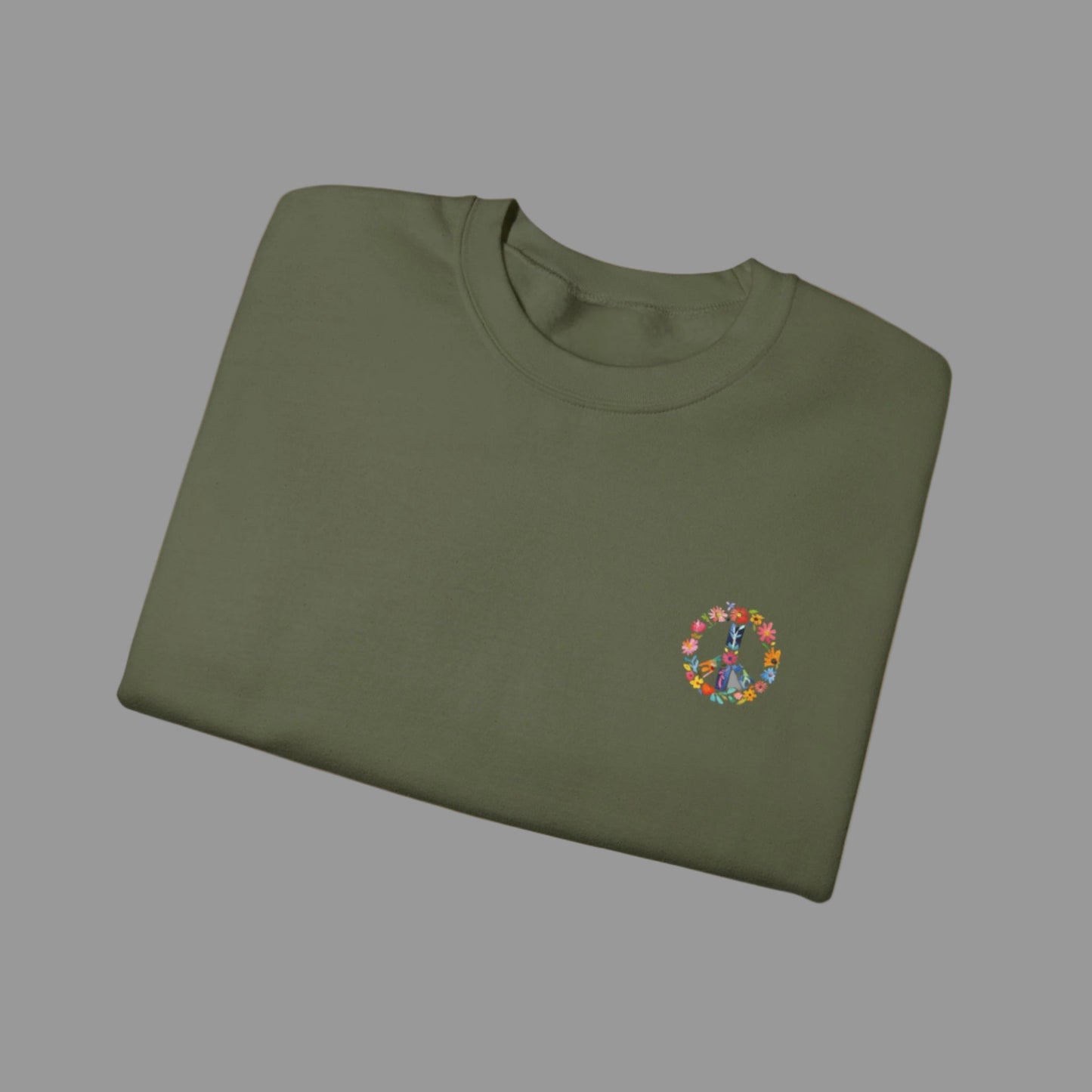 Folded green sweatshirt with a colorful peace symbol design on a white background