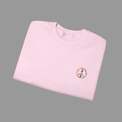 Folded pink sweatshirt with a colorful peace symbol design on a white background