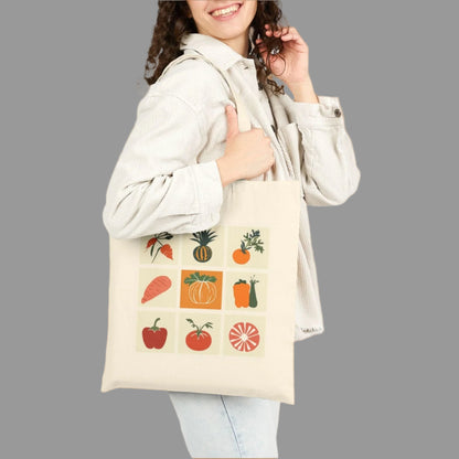 Woman holding a tote bag with fruit and vegetable graphics on a white background