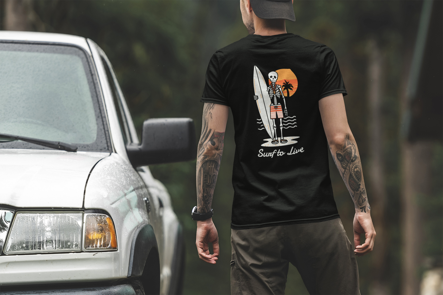 Man wearing a black t-shirt with a graphic design, standing next to a white truck.