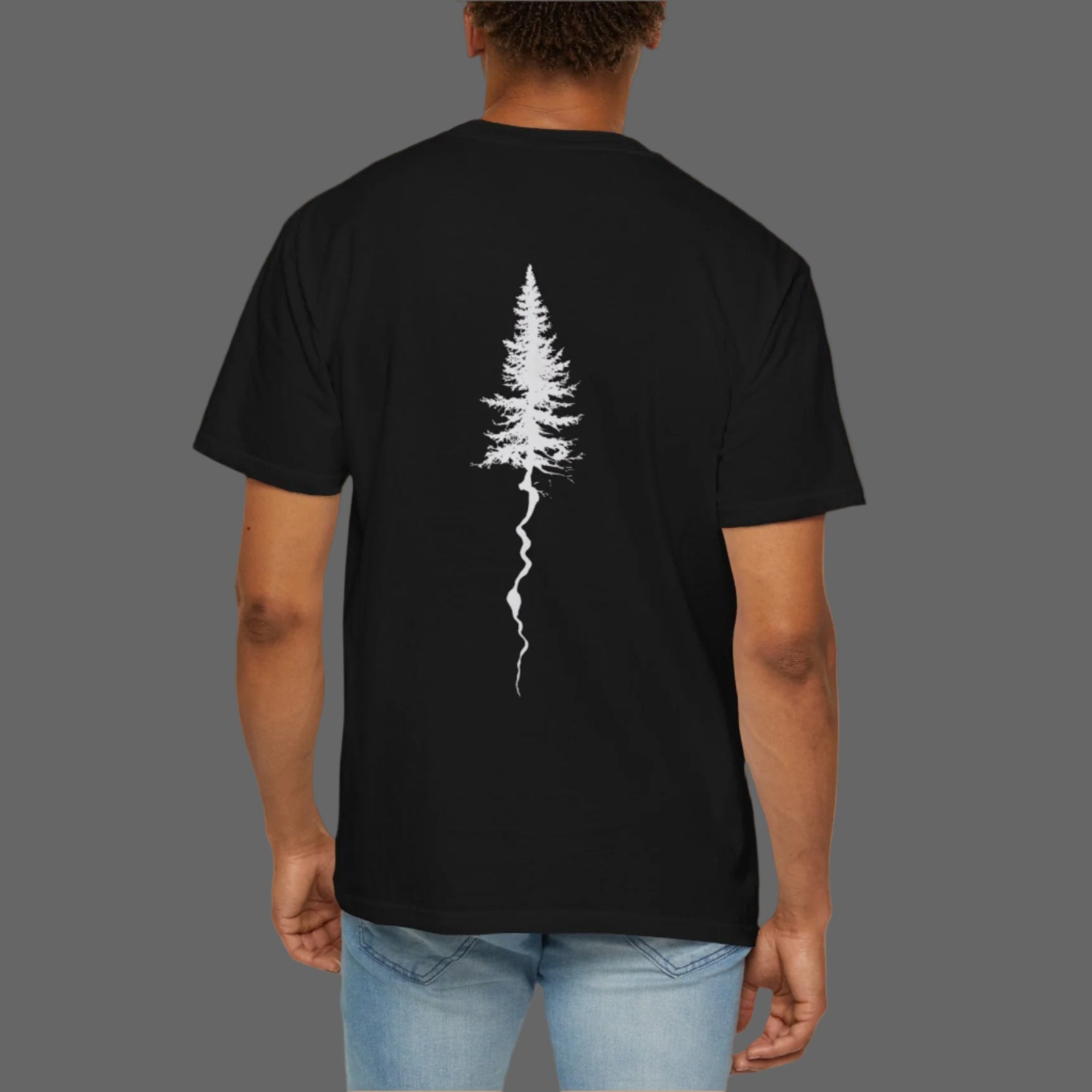 Person wearing a black t-shirt with a white tree design on the back, standing against a white background.