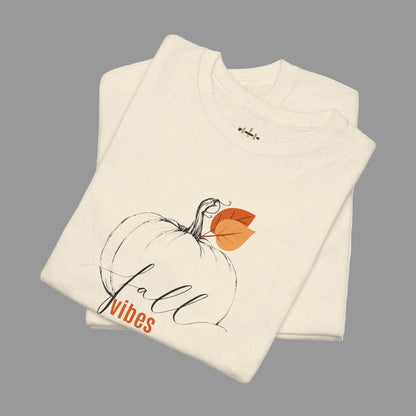 Folded cream-colored shirt with a pumpkin and 'fall vibes' text on a white background