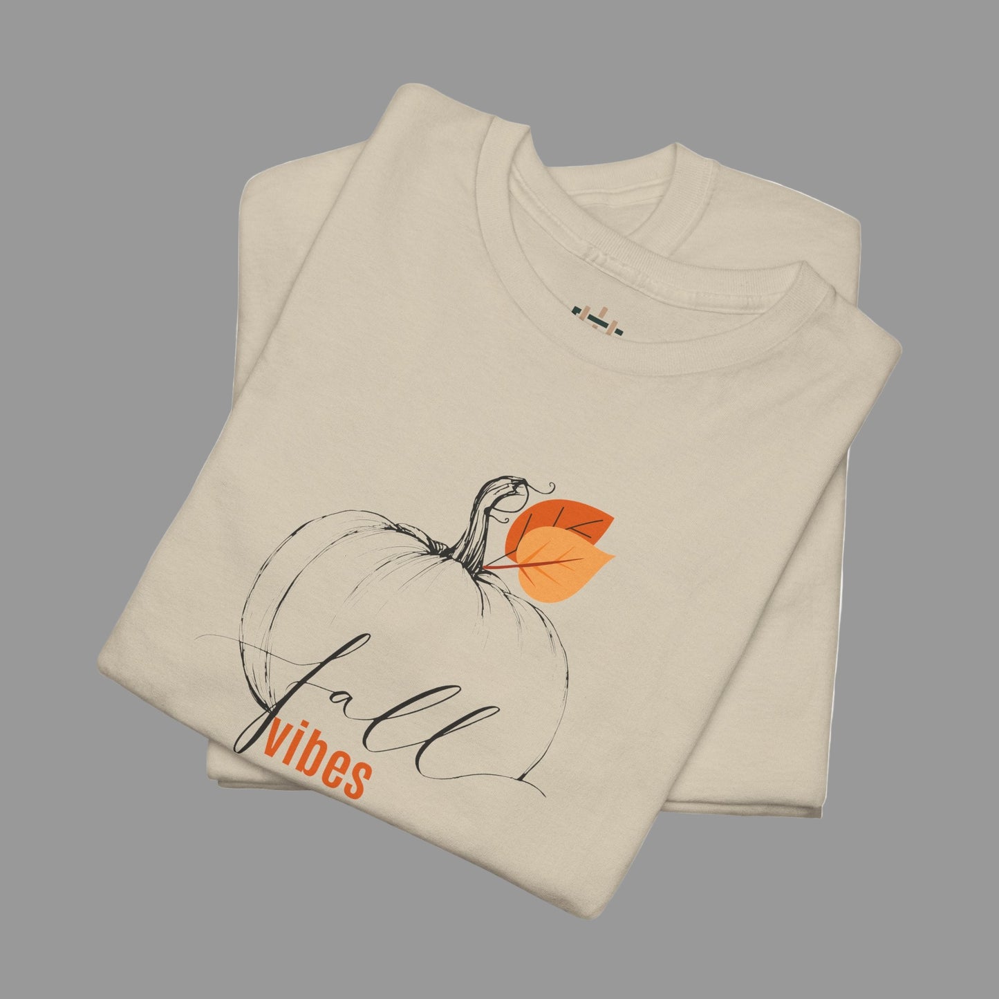 Beige t-shirt with pumpkin and leaf design and 'Fall vibes' text on a white background