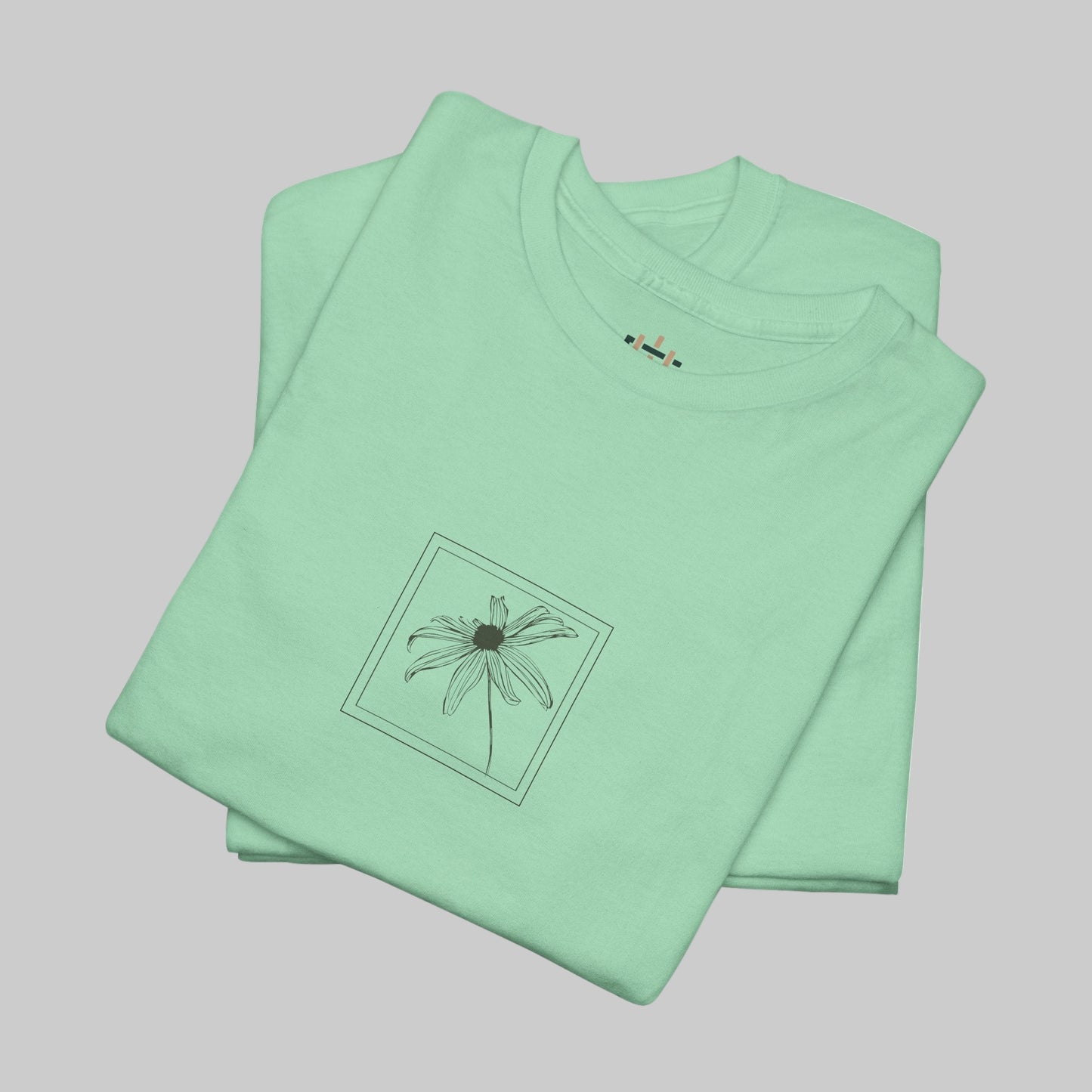 Folded light green t-shirt with a small graphic on a white background