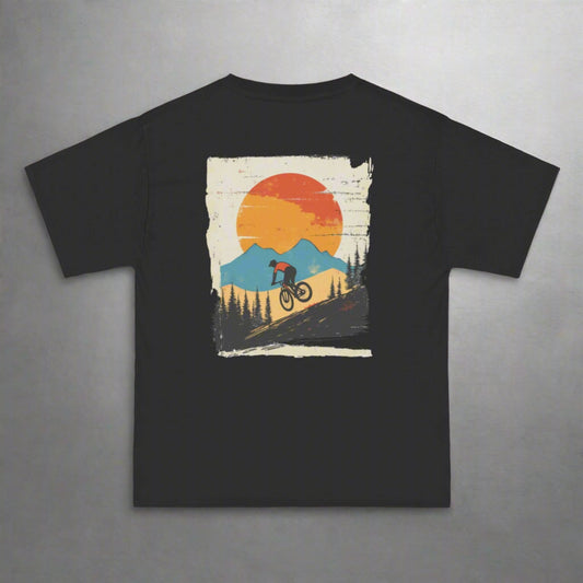A person wearing a black t-shirt with a graphic print of a mountain biker against a sunset backdrop with mountains.