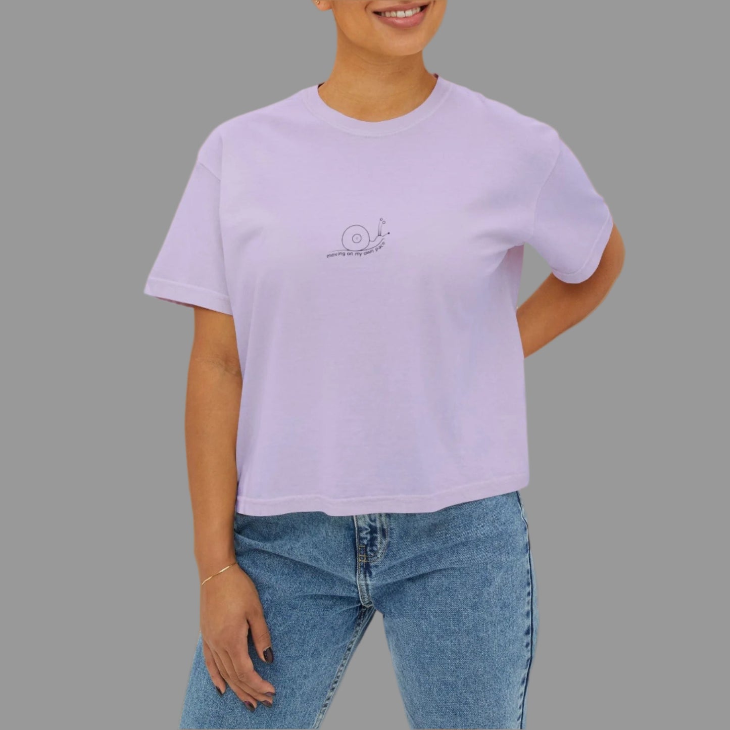 Person wearing a light purple t-shirt with a logo on a white background