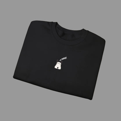 Folded black sweatshirt with a small white graphic and text on a white background