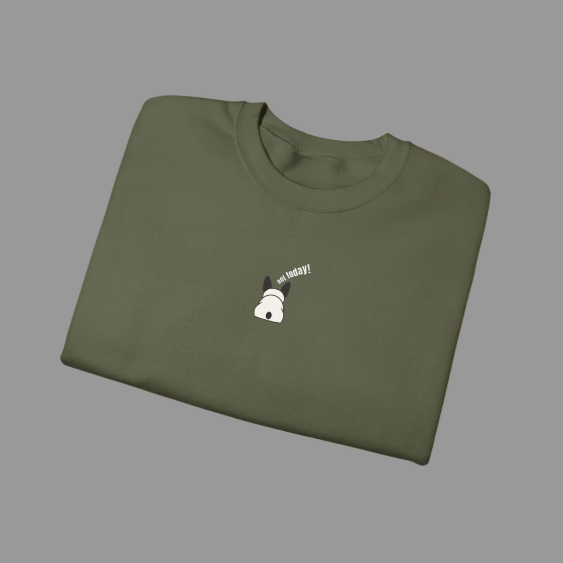Folded green t-shirt with a small white dog graphic and text on a white background