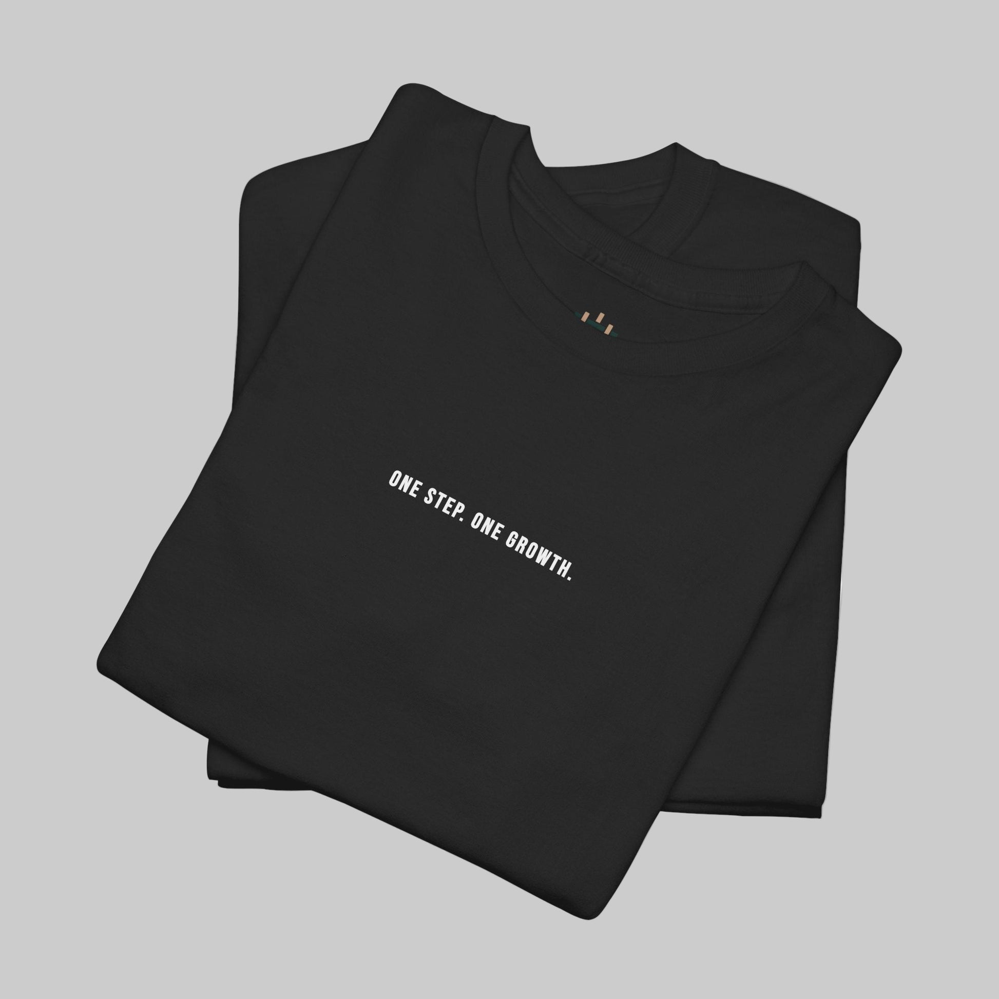 Folded black t-shirt with 'ONE STEP. ONE GROWTH.' text on a white background
