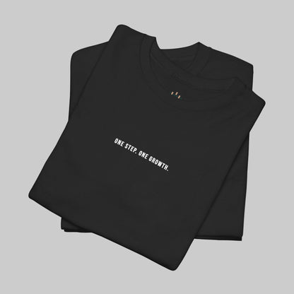 Folded black t-shirt with 'ONE STEP. ONE GROWTH.' text on a white background