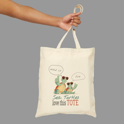Tote bag with sea turtle design and text held by a hand on a white background