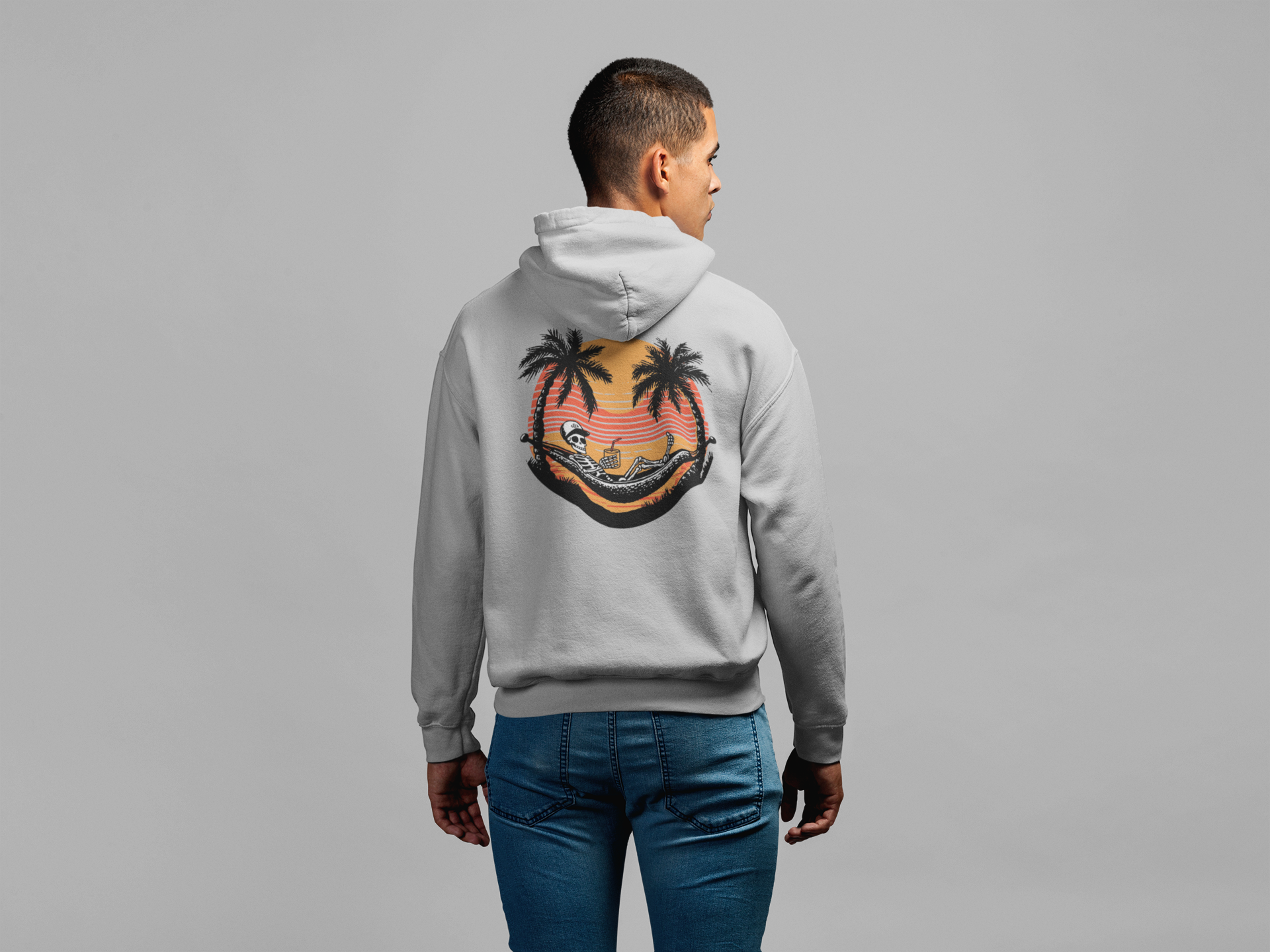 Person wearing a gray hoodie with a palm tree design on the back against a gray background