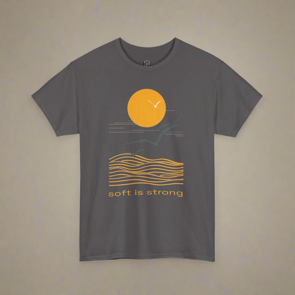 Gray t-shirt with a sunset and wave design and 'soft is strong' text on a white background