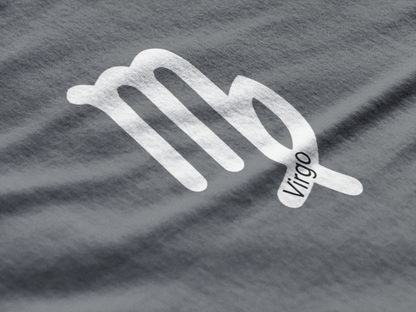 Silver Virgo zodiac sign on a gray fabric background