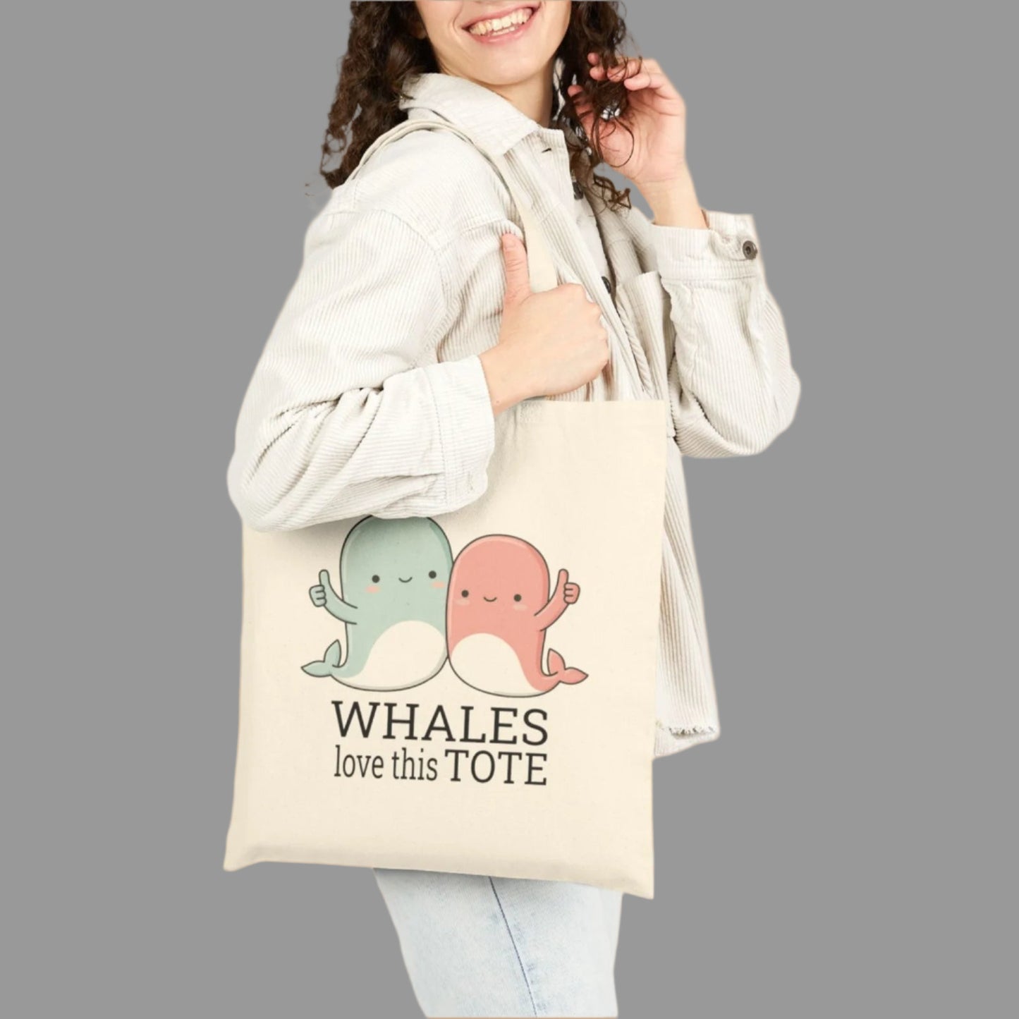 Woman holding a tote bag with cartoon whales and text on a white background