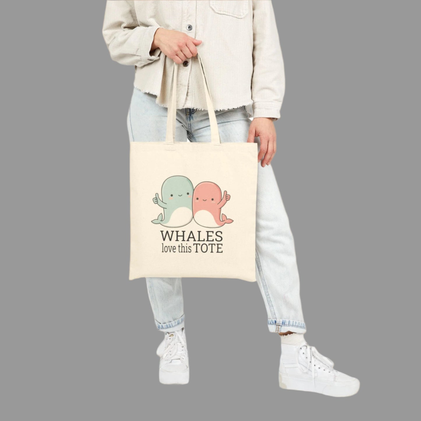 Person holding a tote bag with cartoon whales and text on a white background