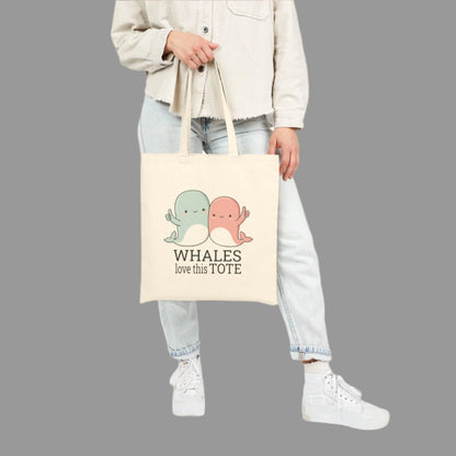Person holding a tote bag with cartoon whales and text on a white background