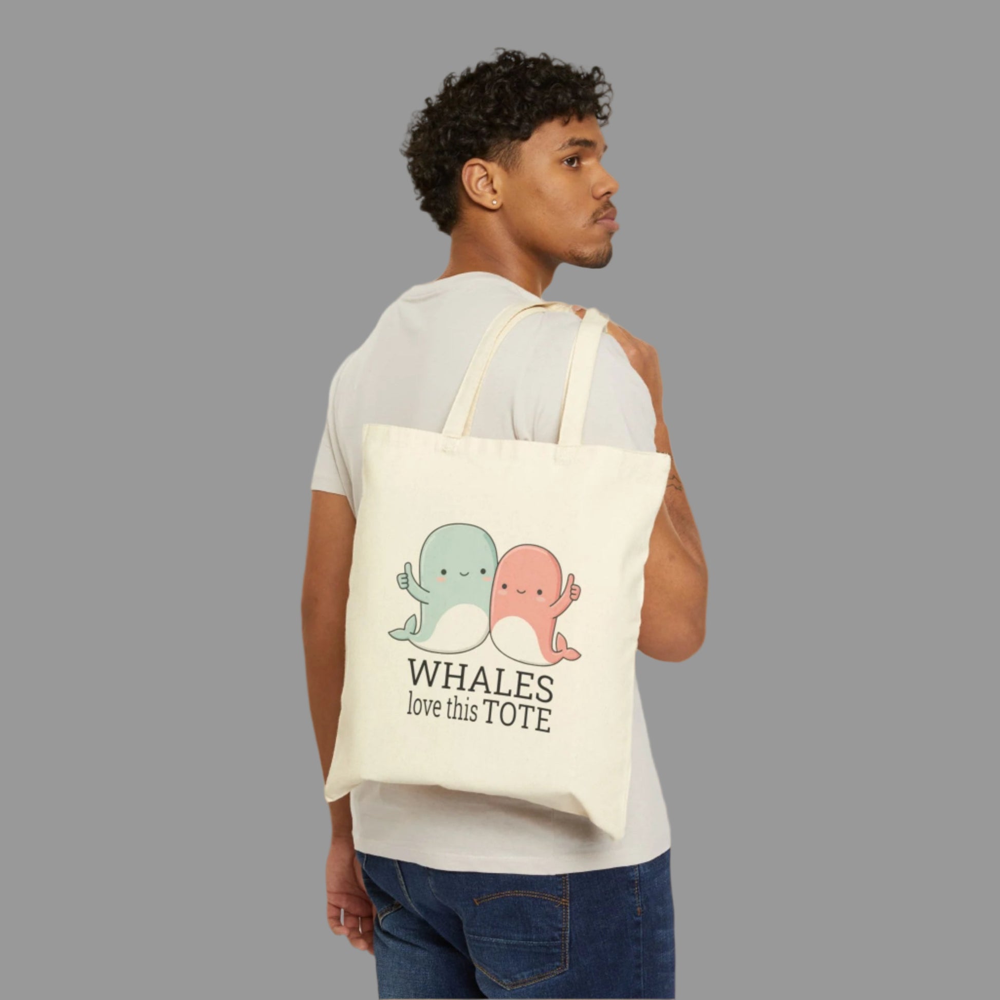 Person holding a tote bag with cartoon whales and text on a white background