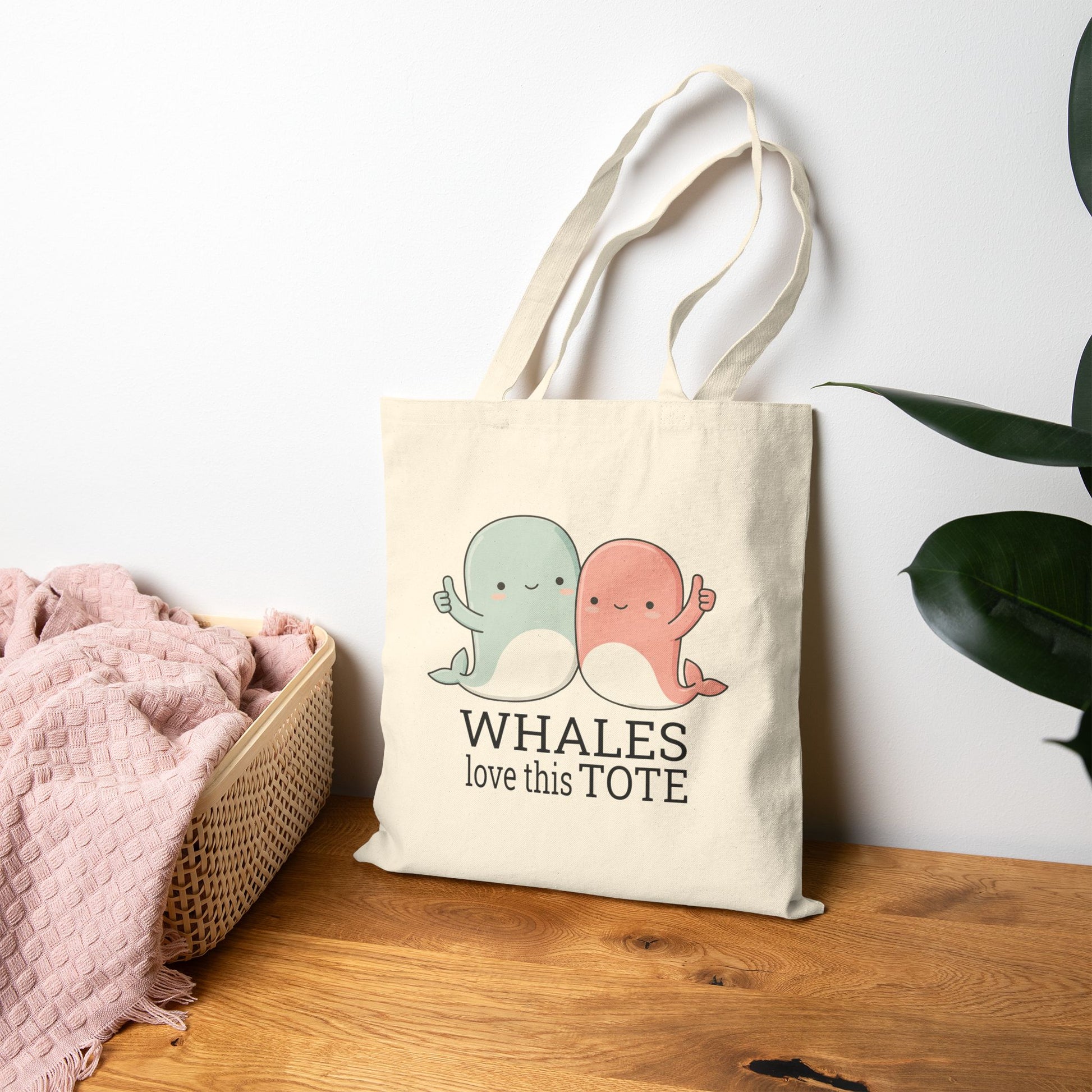 Tote bag with whale design and text on a wooden surface with a white background