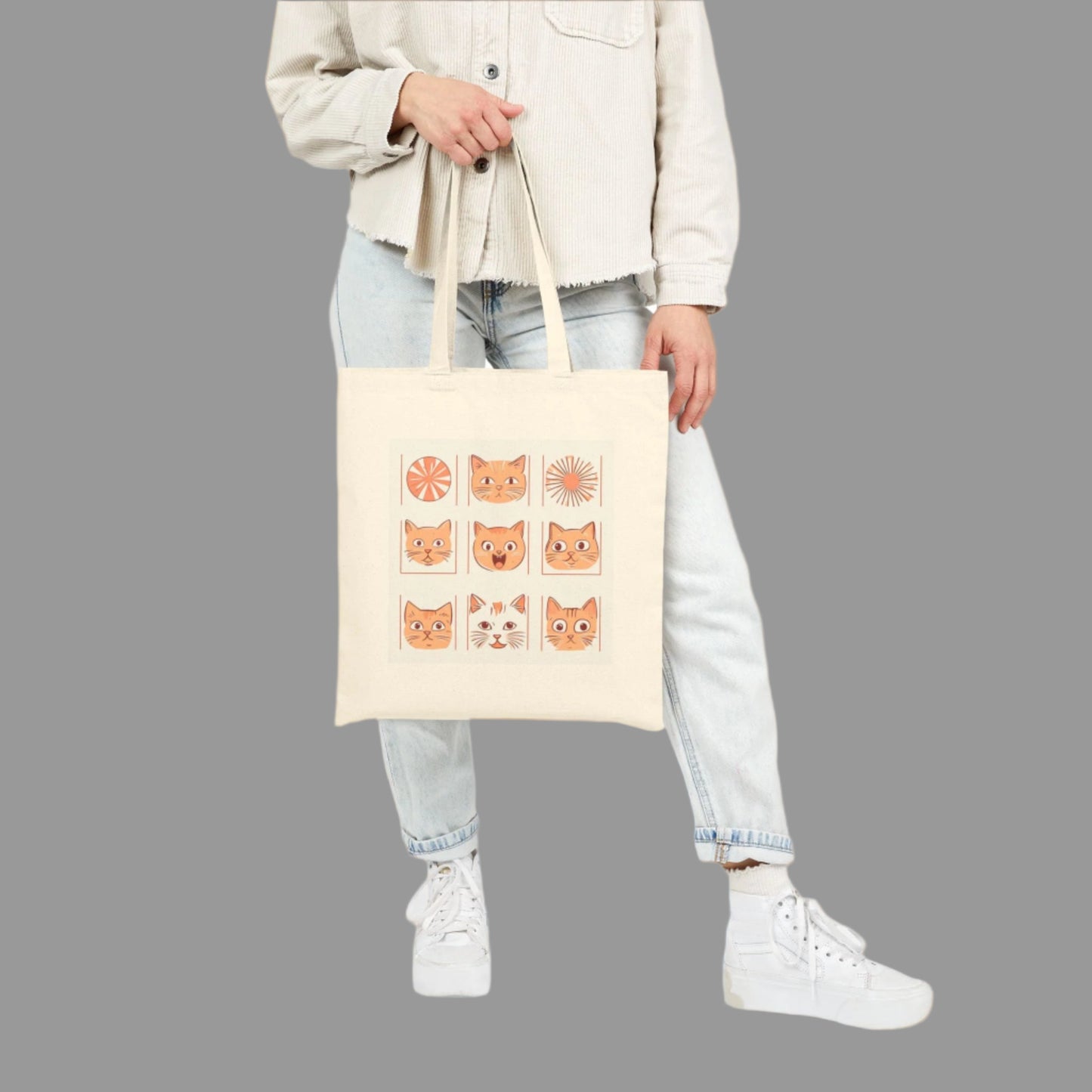 Person holding a tote bag with cat illustrations on a white background