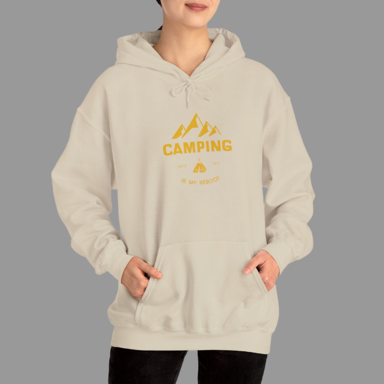 Person wearing a beige hoodie with 'Camping' text and mountain graphic on a white background