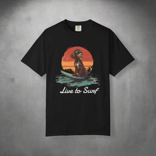 Black t-shirt with a dog on a surfboard graphic and 'Live to Surf' text on a white background