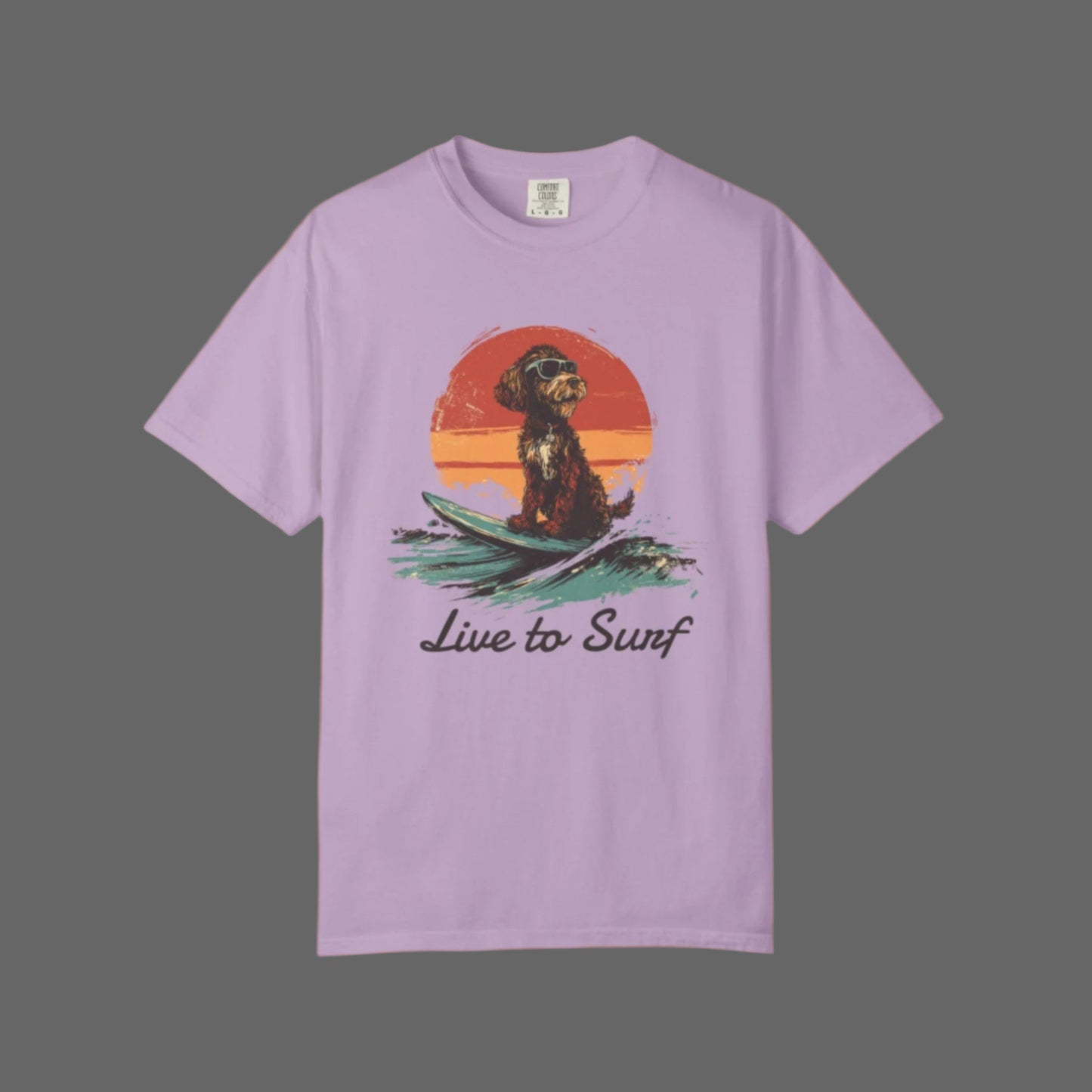 Lavender t-shirt with a graphic of a dog on a surfboard and 'Live to Surf' text, against a white background.