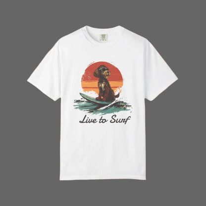 White t-shirt with a graphic of a dog on a surfboard and 'Live to Surf' text, on a white background.